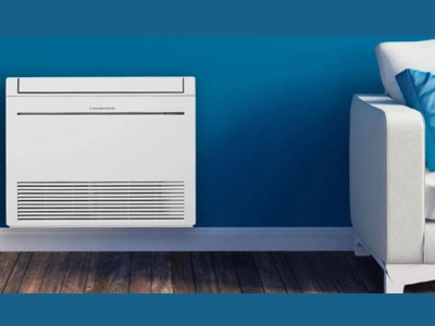 Climatizzatore a pavimento MFZ-KT dal design moderno, installato in soggiorno con parete blu, per comfort e climatizzazione efficiente in Ticino – Frigo Control